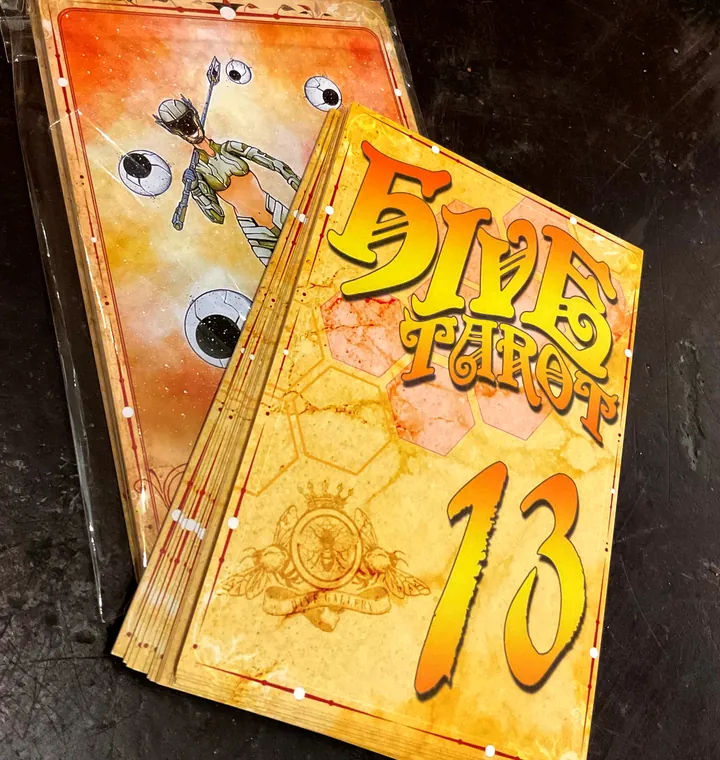 Photo of a printed Hive Tarot deck: the honeycomb card back next to a card face